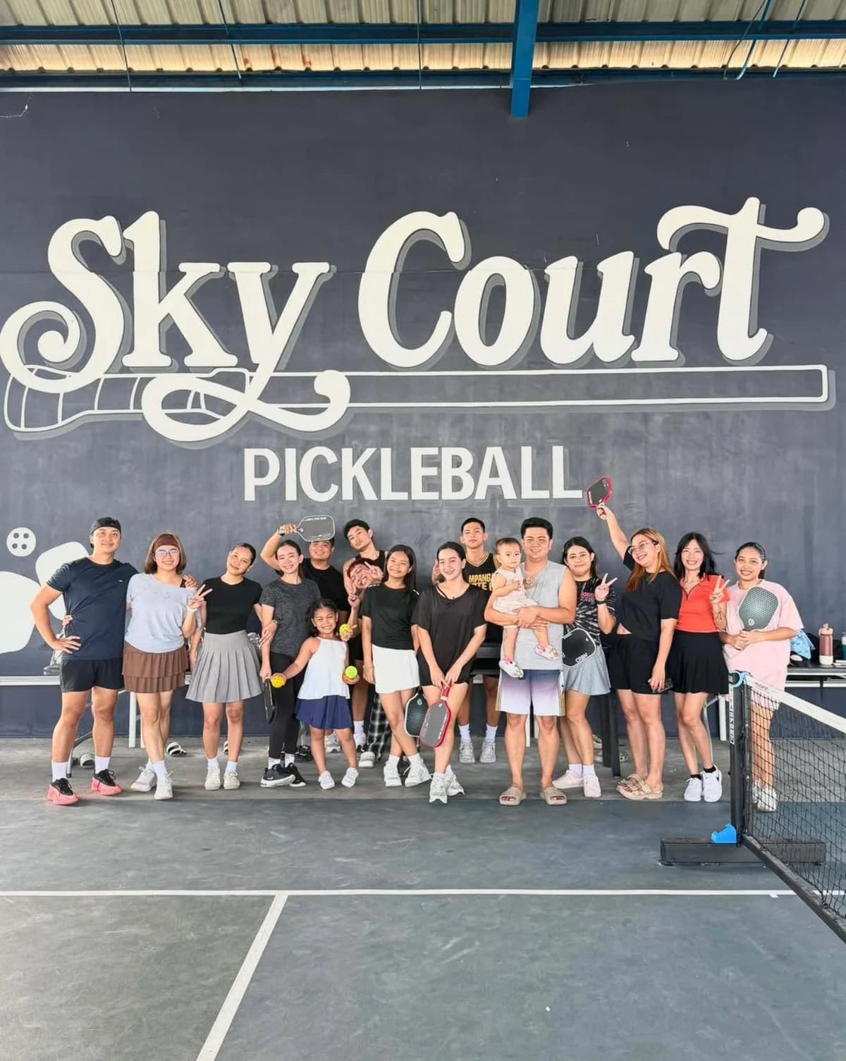 Friends and families gather with pickleball paddles at SkyCourt after a game.