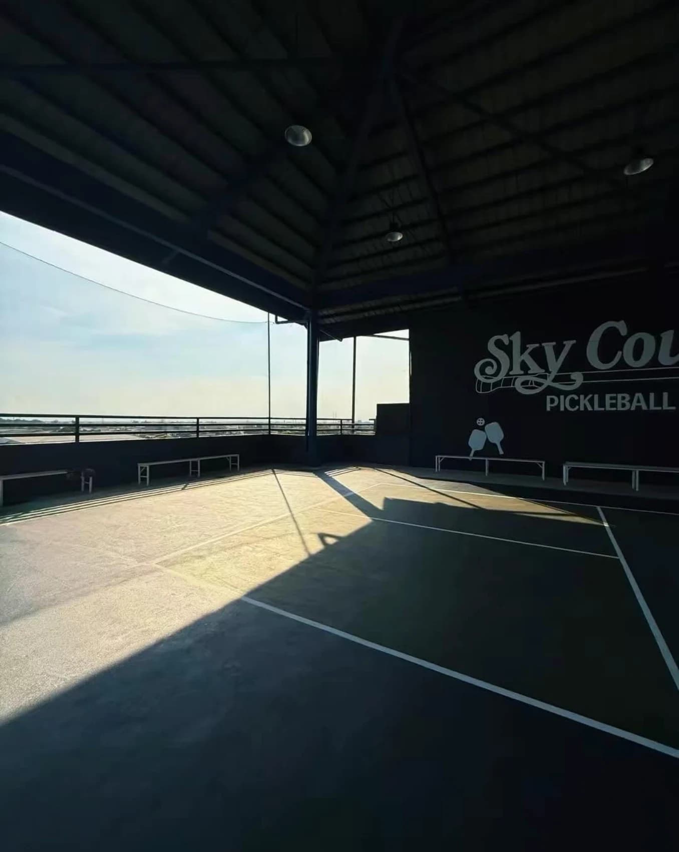 The SkyCourt wall logo and court are silhouetted by warm late-afternoon sunlight.